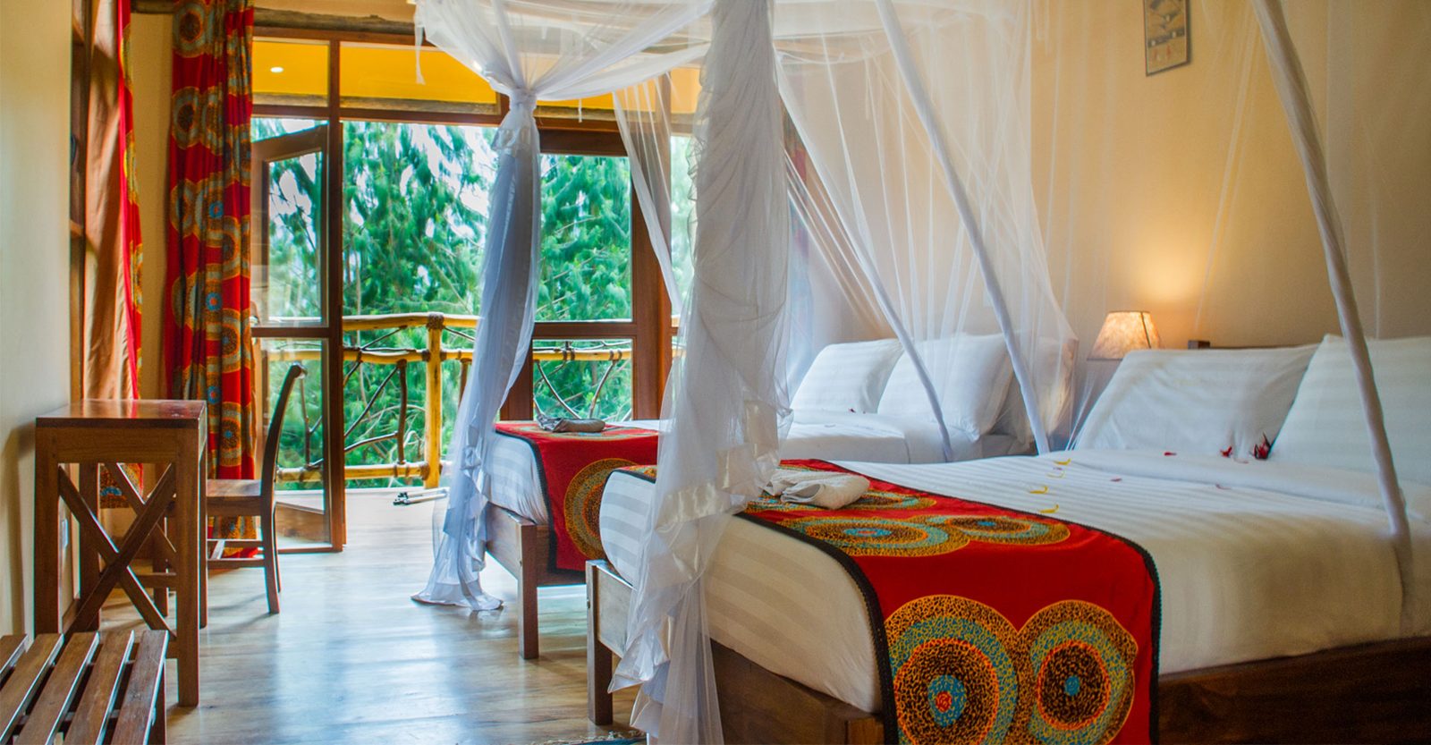 Cottage bedroom with mosquito nets at Ichumbi Gorilla Lodge